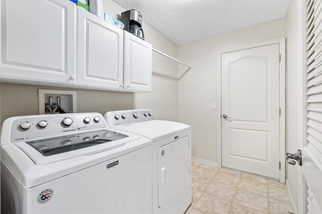 laundry area with light tile patterned flooring, washer and clothes dryer, a textured ceiling, and cabinets