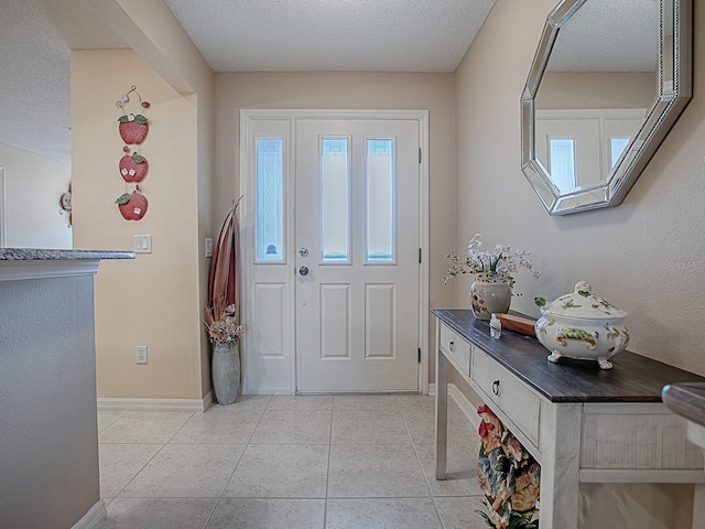 foyer entrance with a textured ceiling, a healthy amount of sunlight, light tile patterned flooring, and baseboards