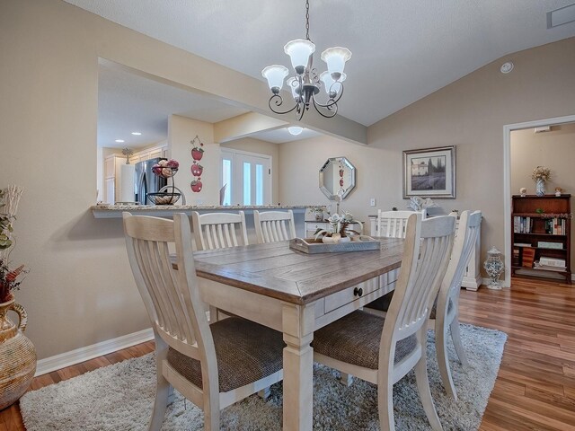 dining room featuring lofted ceiling, a chandelier, and wood-type flooring