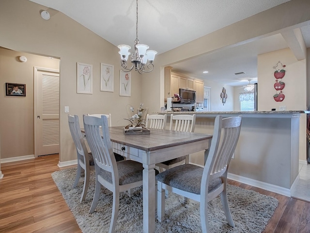 dining room featuring light hardwood / wood-style flooring, a notable chandelier, and lofted ceiling