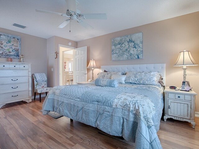 bedroom with hardwood / wood-style flooring, ensuite bathroom, and ceiling fan