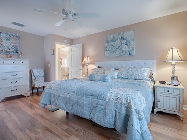 bedroom with ceiling fan, wood finished floors, and visible vents