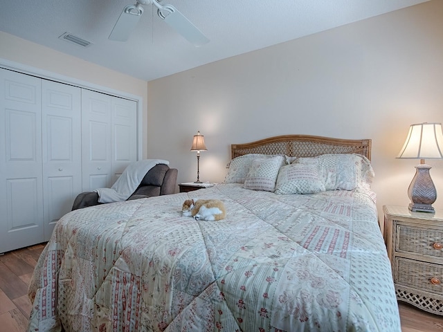 bedroom featuring ceiling fan, a closet, wood finished floors, and visible vents