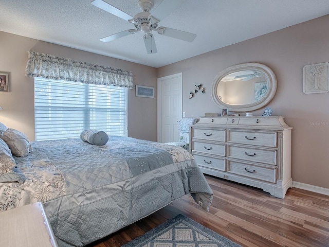 bedroom featuring a ceiling fan, baseboards, a textured ceiling, and light wood finished floors