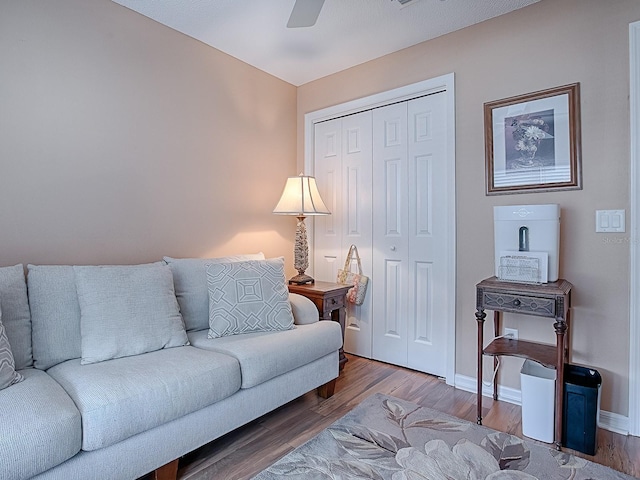 living room featuring ceiling fan, baseboards, and wood finished floors