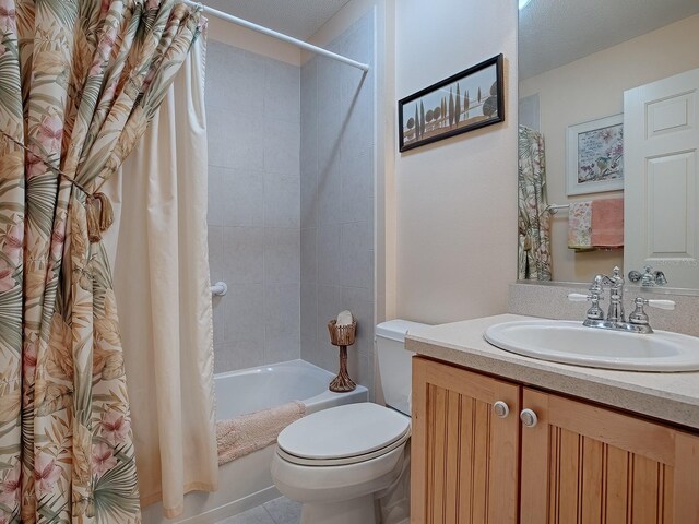 full bathroom with vanity, shower / bath combo with shower curtain, tile patterned flooring, a textured ceiling, and toilet