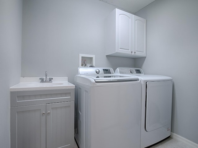 clothes washing area with independent washer and dryer, a sink, cabinet space, and baseboards