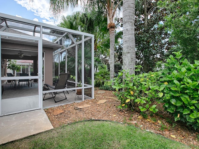 view of yard with glass enclosure, a patio, and ceiling fan