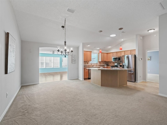 kitchen featuring backsplash, vaulted ceiling, a kitchen island, appliances with stainless steel finishes, and light colored carpet