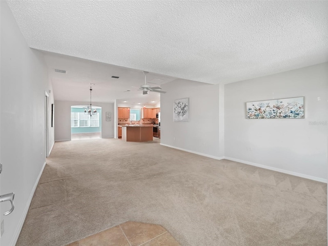 unfurnished living room with ceiling fan with notable chandelier, light colored carpet, and a textured ceiling