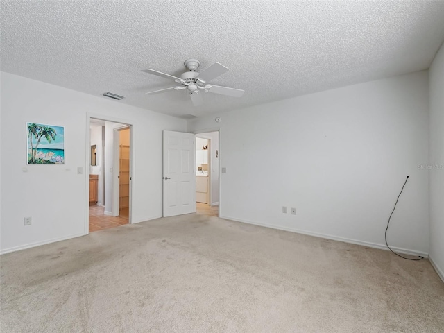 unfurnished bedroom featuring a textured ceiling, light colored carpet, ceiling fan, and washer / dryer