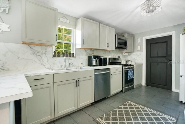 kitchen featuring appliances with stainless steel finishes, sink, light stone countertops, cream cabinets, and tasteful backsplash