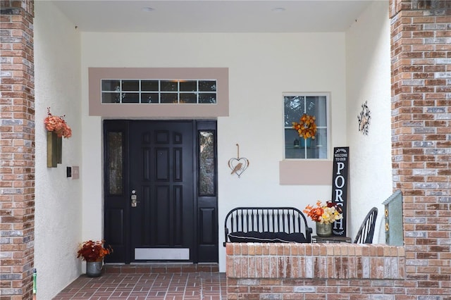 entrance to property featuring stucco siding and brick siding