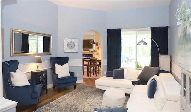 living area featuring arched walkways and wood finished floors