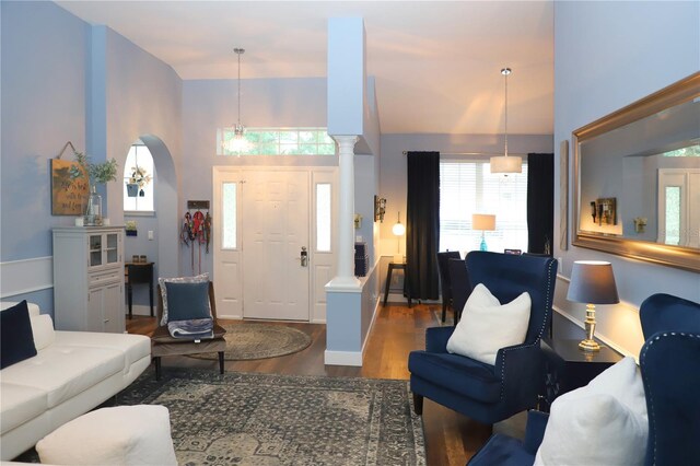 living room featuring decorative columns, hardwood / wood-style floors, and a high ceiling