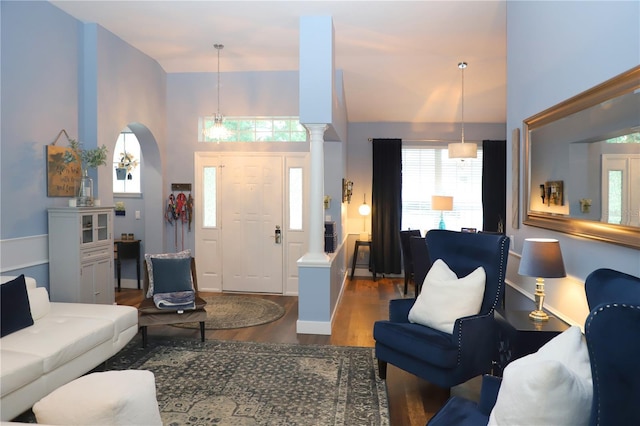 living area featuring decorative columns, a high ceiling, arched walkways, and wood finished floors