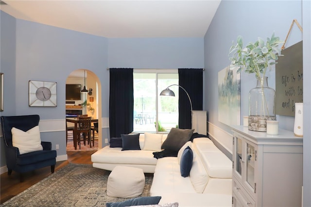 living room with arched walkways and wood finished floors