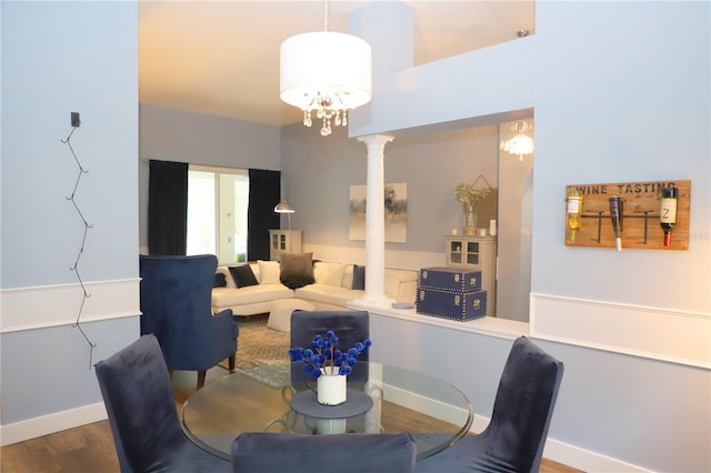 dining space featuring baseboards, ornate columns, and wood finished floors