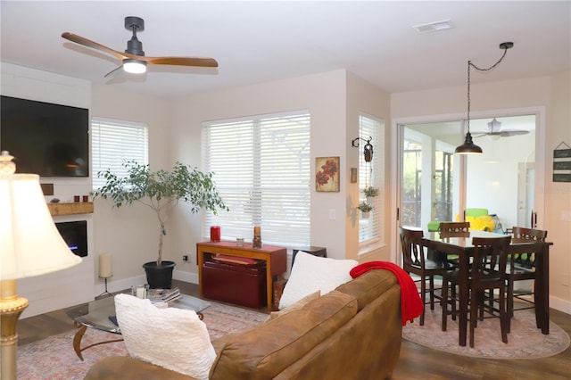 living room with baseboards, ceiling fan, visible vents, and wood finished floors