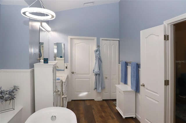 bathroom with vaulted ceiling, hardwood / wood-style flooring, a tub, and vanity