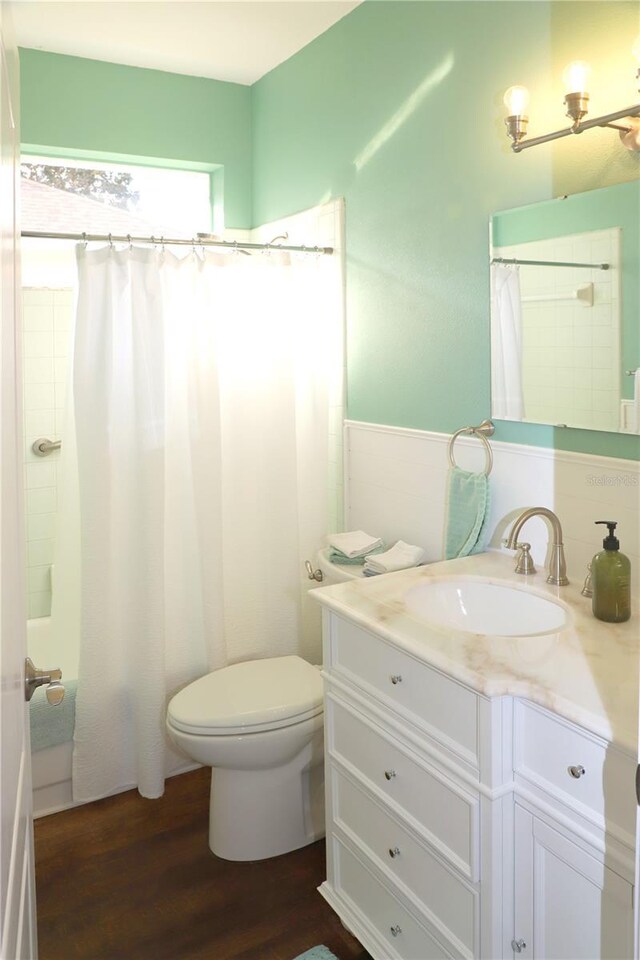 bathroom with toilet, a shower with curtain, wood finished floors, and vanity