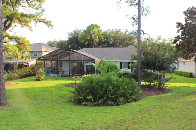 rear view of house featuring glass enclosure and a lawn