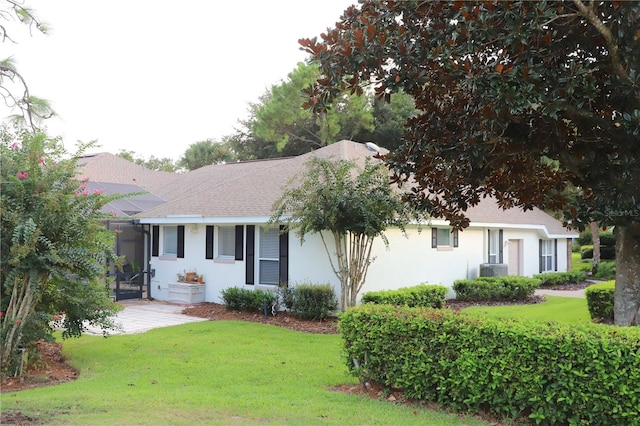 ranch-style house with central AC unit, a front yard, and a sunroom