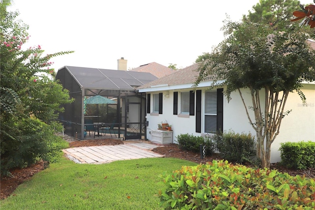 back of property with glass enclosure, a patio area, and a yard