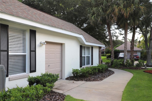 doorway to property featuring roof with shingles and stucco siding