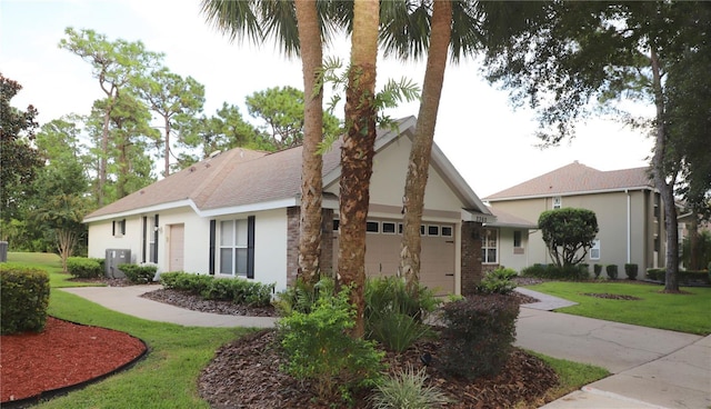 view of front of house featuring concrete driveway, stucco siding, an attached garage, a front yard, and brick siding