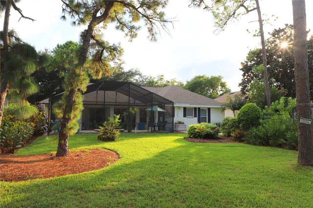 back of house with glass enclosure and a yard