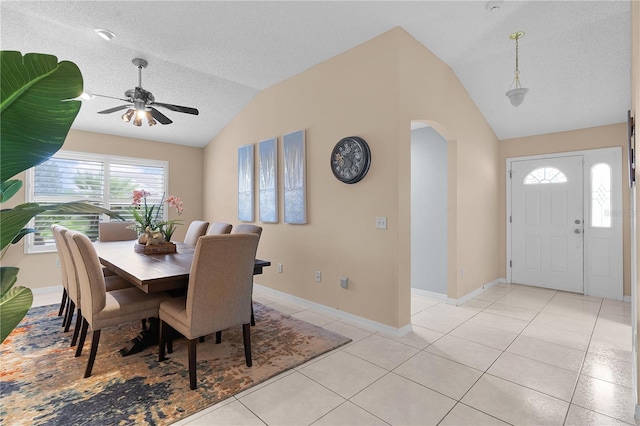 dining space featuring light tile patterned flooring, vaulted ceiling, a textured ceiling, and ceiling fan