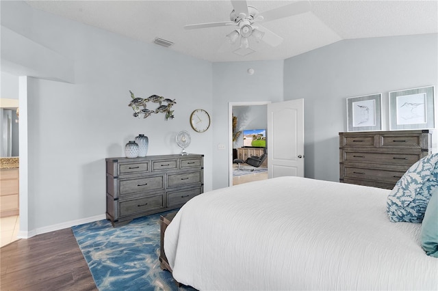 bedroom featuring ensuite bath, dark hardwood / wood-style floors, a textured ceiling, ceiling fan, and lofted ceiling