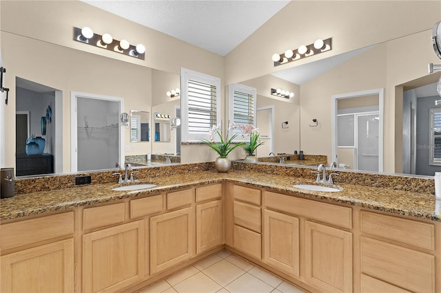 bathroom with tile patterned flooring, walk in shower, vanity, and lofted ceiling