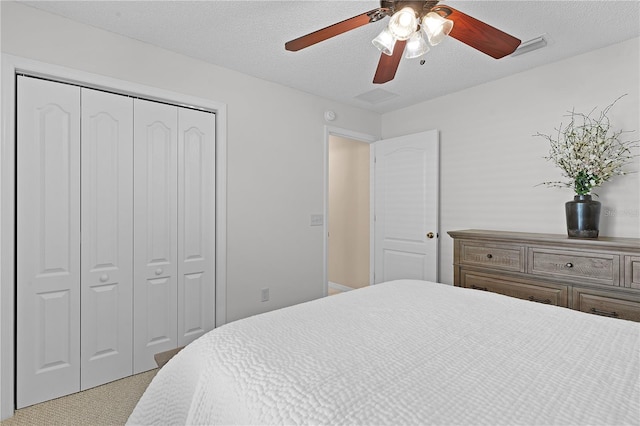 carpeted bedroom with ceiling fan, a closet, and a textured ceiling