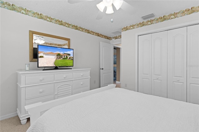 bedroom with ceiling fan, a closet, a textured ceiling, and carpet floors