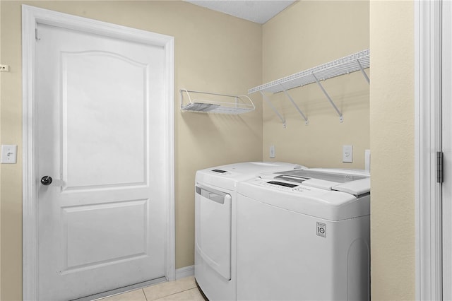 clothes washing area with light tile patterned flooring and separate washer and dryer