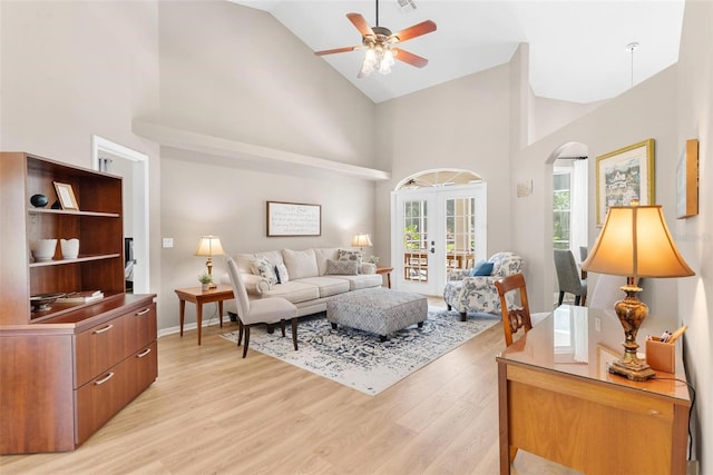 living room with light wood-type flooring, french doors, high vaulted ceiling, and ceiling fan