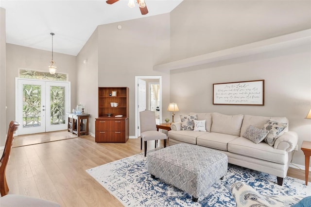 living room featuring light wood-type flooring, ceiling fan, high vaulted ceiling, and french doors