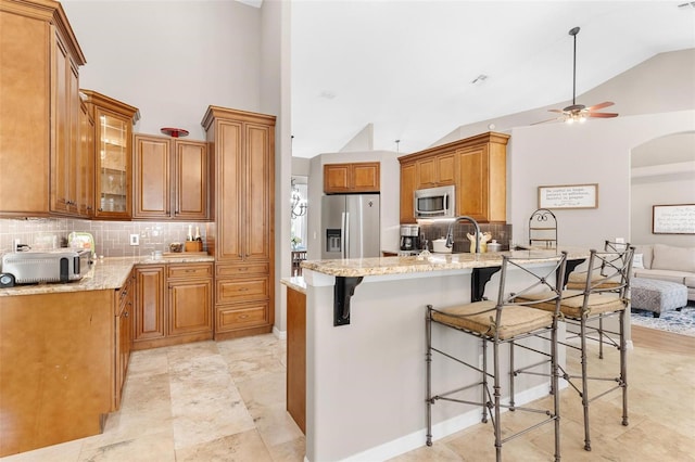 kitchen featuring appliances with stainless steel finishes, kitchen peninsula, light stone countertops, and ceiling fan