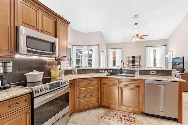 kitchen with ceiling fan with notable chandelier, appliances with stainless steel finishes, kitchen peninsula, sink, and decorative backsplash