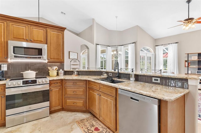 kitchen featuring vaulted ceiling, ceiling fan with notable chandelier, backsplash, appliances with stainless steel finishes, and sink