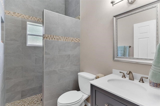 bathroom with vanity, toilet, and a tile shower