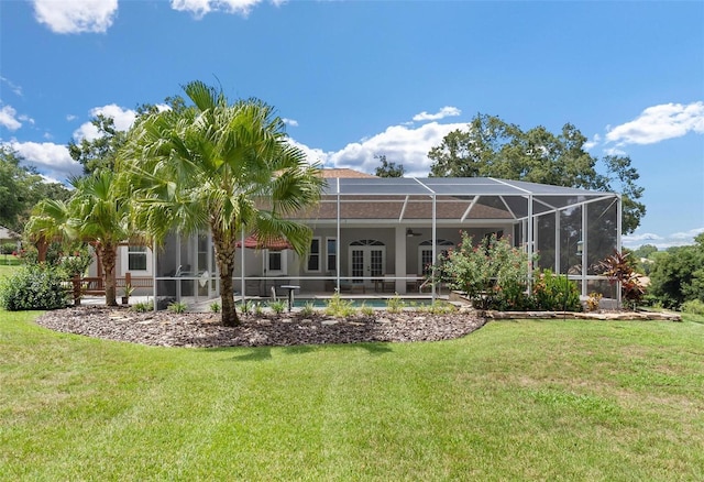 rear view of property featuring a lawn, a patio, and a lanai