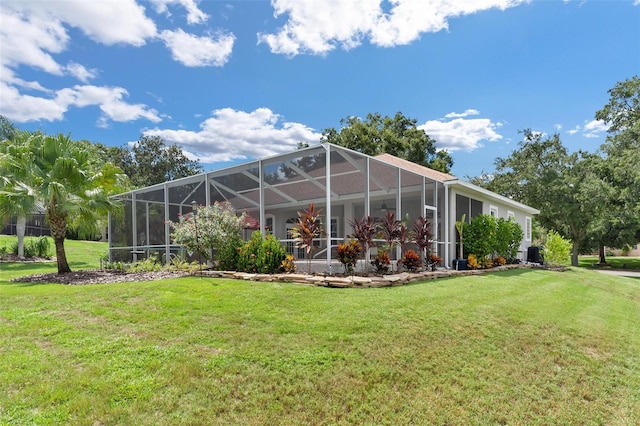 rear view of property featuring a yard and glass enclosure