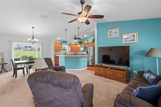 living room featuring ceiling fan with notable chandelier, vaulted ceiling, sink, and light carpet