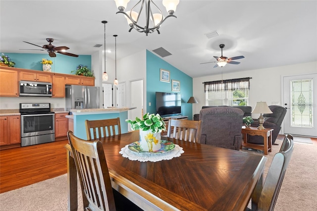 dining room featuring vaulted ceiling, ceiling fan with notable chandelier, and visible vents