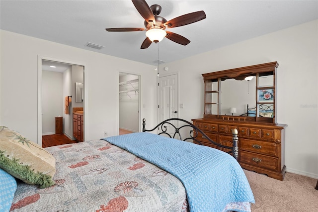 bedroom featuring ceiling fan, ensuite bathroom, light colored carpet, visible vents, and a closet