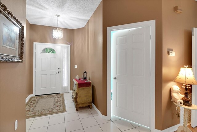 32915 Crooked Oaks Ln, Leesburg, FL 34748 - foyer entrance featuring a textured ceiling, light tile patterned flooring, an inviting chandelier, and baseboards