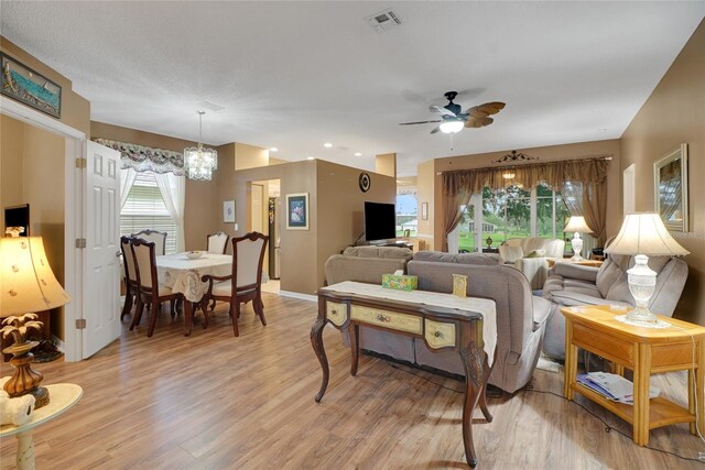 32915 Crooked Oaks Ln, Leesburg, FL 34748 - living room featuring light wood finished floors, baseboards, visible vents, and ceiling fan with notable chandelier